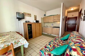 A compact kitchen with wooden cabinets, a microwave, and a small television.
