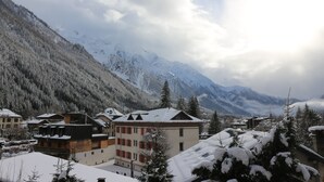 Un pueblo montañoso con edificios y árboles cubiertos de nieve, que presenta una mezcla de arquitectura tradicional y moderna.