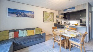 Una sala de estar moderna con sofá, mesa de comedor y zona de cocina.
