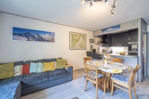 Un salon moderne comprenant un canapé, une table à manger et un coin cuisine.