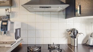 Una cocina equipada con cafetera, microondas, estufa a gas y campana extractora.