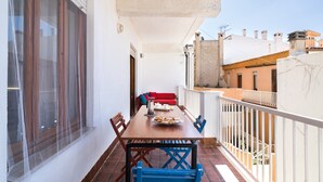 Ein Balkon mit Esstisch, Stühlen und einer roten Couch.