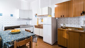 Eine Küche mit Tisch, Stühlen, einem Kühlschrank und Holzschränken.