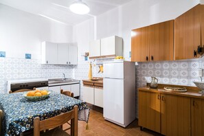 Een keuken met een tafel, stoelen, een koelkast en houten kastjes.