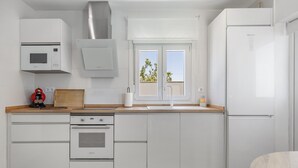 A modern kitchen with white cabinetry, a built-in oven, a microwave, and a refrigerator. - Casita Meraki 3 with Heated Indoor Pool, Garden, Terrace, and Wi-Fi (Chiclana de la Frontera)