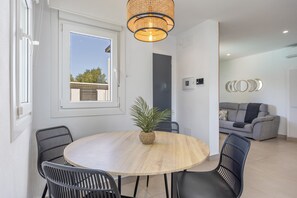 A dining area with a round table, black chairs, a potted plant, and a modern pendant light.