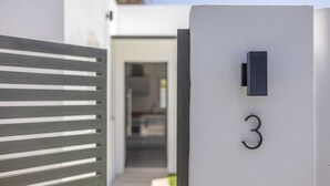 A modern building with a number '3' sign, a metal gate, and a door leading to an interior space. - Casita Meraki 3 with Heated Indoor Pool, Garden, Terrace, and Wi-Fi (Chiclana de la Frontera)