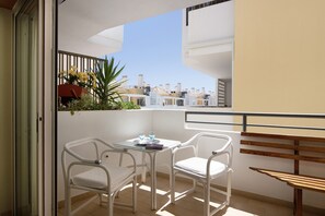 A balcony with a table and chairs, a bench, and a view of buildings.
