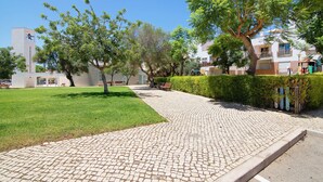 Un sendero pavimentado, césped verde y árboles en una zona residencial.