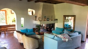 Una sala de estar con chimenea, un sofá, una silla y una mesa de centro.