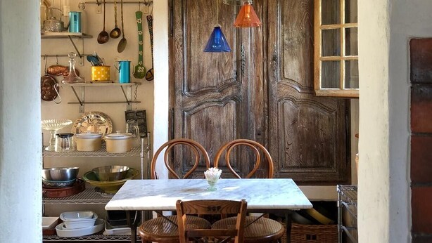 Una cocina rústica con vigas de madera, una puerta de madera y una mesa de comedor con sillas.