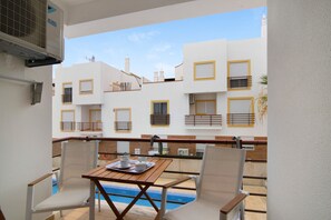 A balcony with a pool, white walls, and yellow window frames.