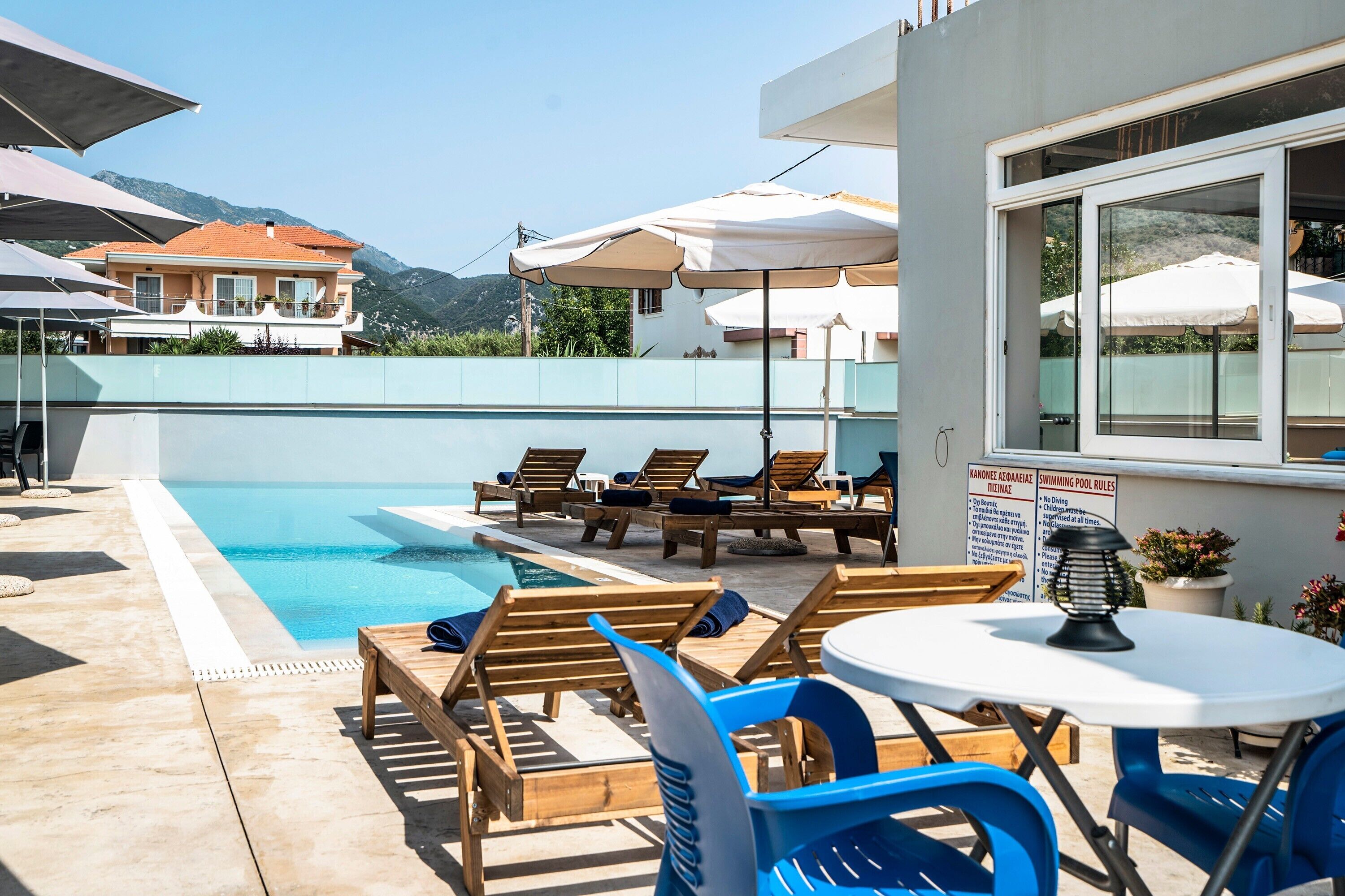 Área da piscina com espreguiçadeiras, guarda-sóis e uma placa com as regras da piscina.