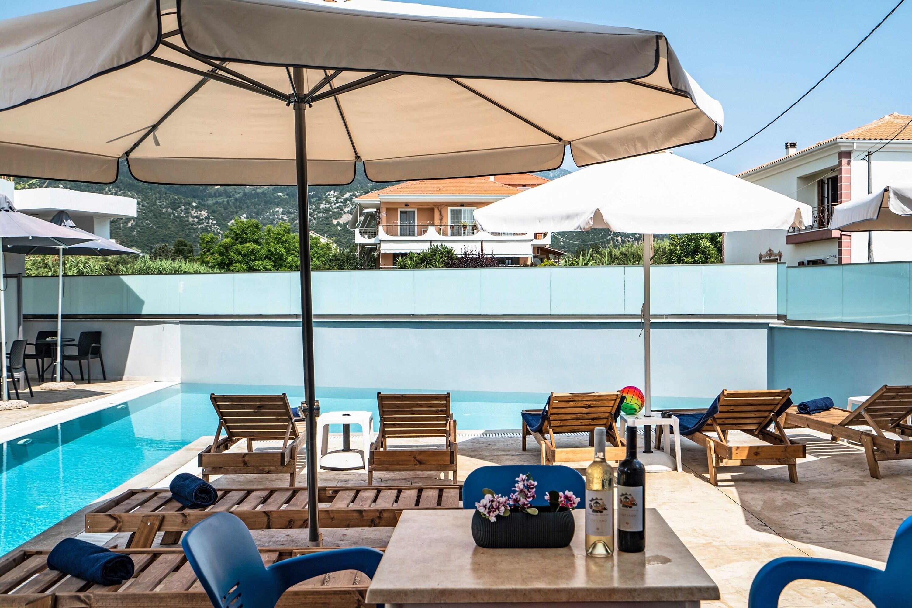 A poolside area with lounge chairs, umbrellas, and a table with a bottle.