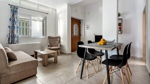 Un soggiorno moderno con divano, tavolino, tavolo da pranzo con sedie e una porta in legno.