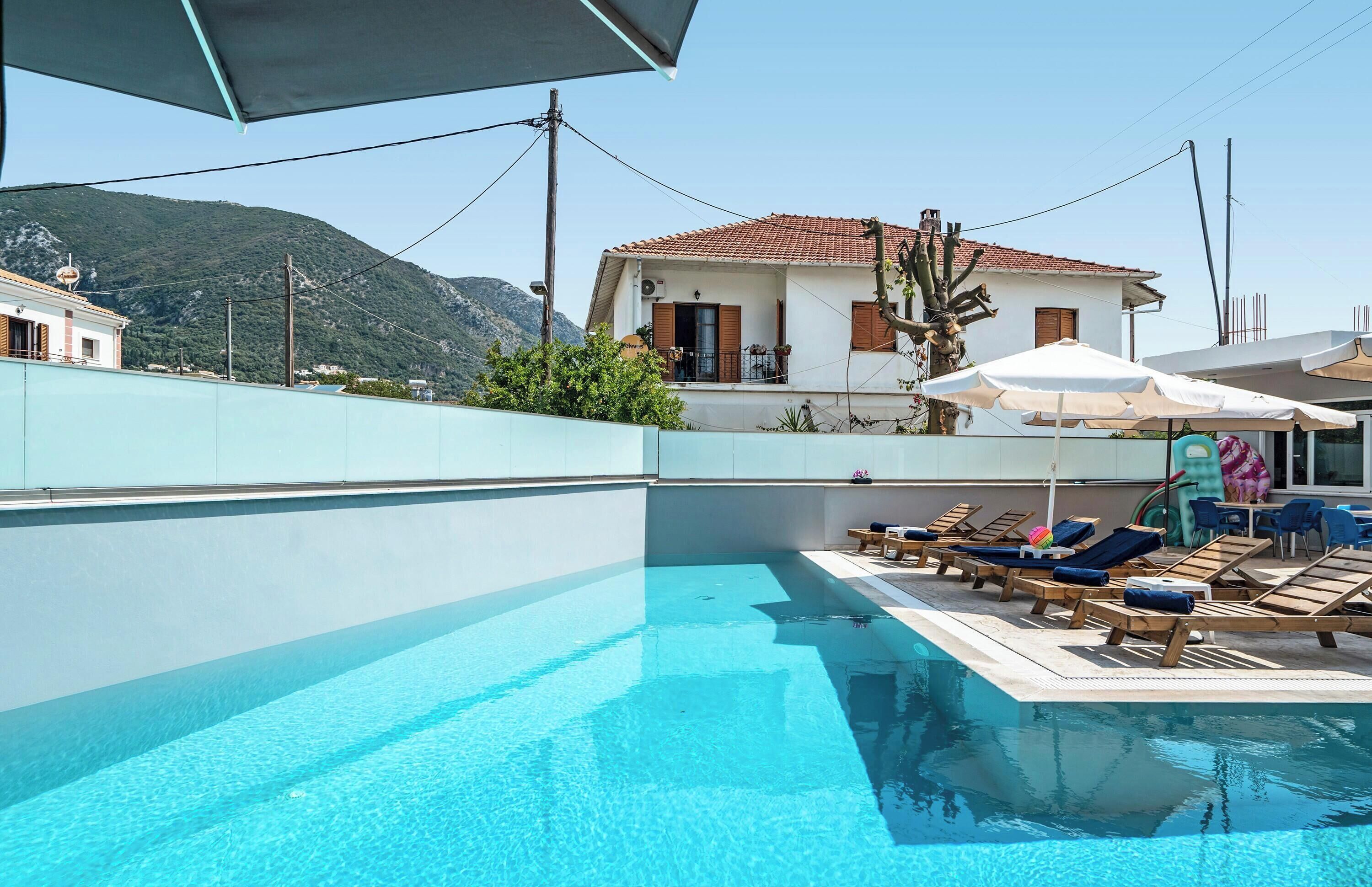 Ein Swimmingpool mit Liegestühlen, einem Sonnenschirm und einem Berg im Hintergrund.