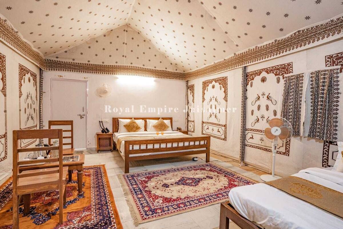 A bedroom with a wooden bed, a nightstand, a chair, a fan, and patterned walls.