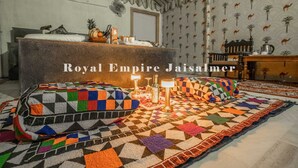 Una habitación con un sofá a cuadros, una alfombra estampada y una pared decorativa.