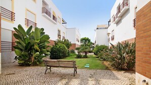 Une cour avec un banc, des plantes en pot et un mur de briques.