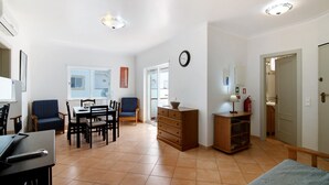 Un vaste espace de vie comprenant une table à manger, des chaises, un canapé, un meuble en bois et une horloge murale.