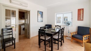 Un espace repas comprenant une table, des chaises, un ventilateur et une vue sur l’extérieur.
