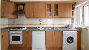 Une cuisine équipée de meubles en bois, d’une cuisinière, d’un four, d’un lave-vaisselle et d’une machine à laver.