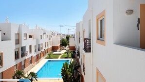 Un edificio residencial con piscina, balcones y cielo despejado.