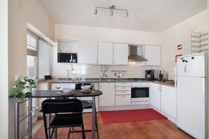 A modern kitchen with white cabinets, a stainless steel sink, a microwave, and a refrigerator.