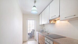 A kitchen with white cabinets, a granite countertop, a built-in oven, and a pendant light. - Apartment 'Royal Cabanas Golf 88' with Shared Pool, Shared Garden and Air Conditioning (Cabanas de Tavira)