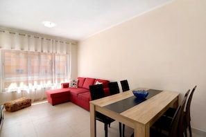 A living room with a red sofa, a wooden dining table, and a blue bowl.