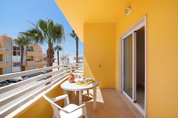 A balcony with a table, chairs, and a vase.