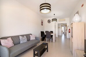 Ein modernes Wohnzimmer mit einer Couch, einem Couchtisch und einem Schreibtisch mit Stühlen.