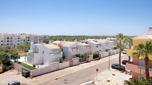 Un quartier résidentiel avec des maisons modernes, un ciel dégagé et un panneau de signalisation indiquant un arrêt sur la route.