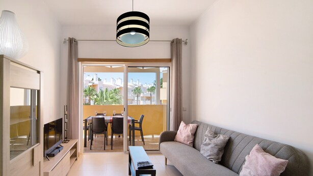 Un salon moderne avec un canapé, un téléviseur et un coin repas.