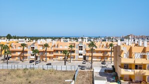 Een woongebied met meerdere gele gebouwen, palmbomen en een helderblauwe lucht.