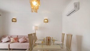 A dining area with a glass table, chairs, and a sofa with cushions. - Holiday Apartment "Urbanização Lagar 133" with Sea View & Private Balcony (Conceição de Tavira)