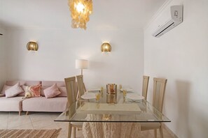 Un coin repas avec une table en verre, des chaises et un canapé agrémenté de coussins.