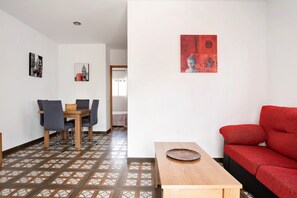 Une pièce comprenant une table à manger, des chaises, un canapé et un mur rouge orné d’œuvres d’art.