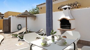 An outdoor patio with a table set for two, a grill, and a water fountain. - Holiday Home 'Casa Cala Del Aceite 1' with Private Pool, Private Terrace and Wi-Fi (Conil de la Frontera)