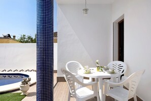 A poolside area with a white table and chairs, a blue tiled column, and a small pool.