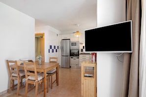 Une cuisine moderne équipée d’un téléviseur à écran plat, d’une table à manger en bois, de chaises et d’un réfrigérateur.