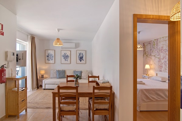 Une pièce moderne et bien éclairée, comprenant une table à manger, des chaises, un canapé et un lit.