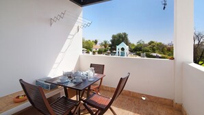 A balcony with a table set for tea, chairs, and a view of a residential area.