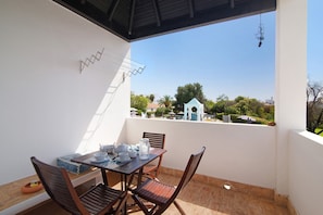 A balcony with a table set for tea, chairs, and a view of a residential area. - Vacation Home 'Quinta Velha Village 134" with Balcony, Shared Pool & A/C (Cabanas de Tavira)