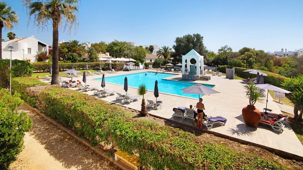 A resort with a swimming pool, sun loungers, and a gazebo.