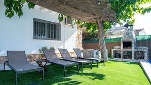A patio with four lounge chairs, a stone fireplace, and a pool. - Villa "Traditional" with Private Pool & Wi-Fi (Creixell)