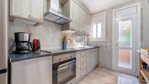 A modern kitchen with a built-in oven, a coffee maker, and wooden cabinets. - Villa "Traditional" with Private Pool & Wi-Fi (Creixell)