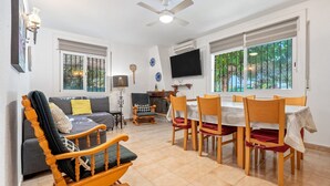 A living room with a sofa, a rocking chair, a dining table with chairs, a ceiling fan, and a TV mounted on the wall. - Villa "Traditional" with Private Pool & Wi-Fi (Creixell)