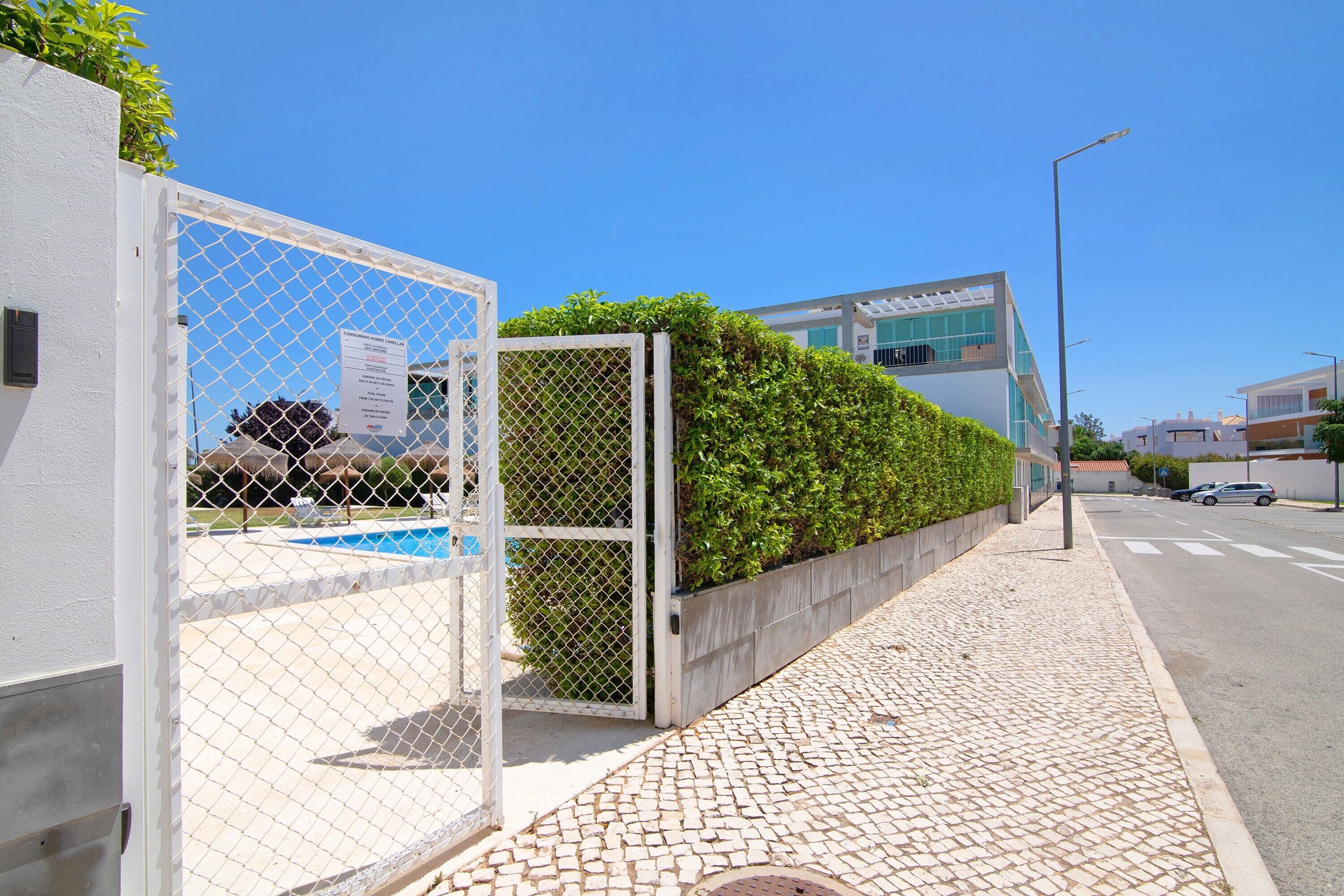 A gated area with a pool, a paved walkway, and a modern building in the background.
