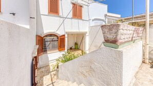 A white building with wooden shutters, a stone staircase, and a small garden area. - Apartment "Casa di Marika" with Private Terrace and Air Conditioning (marina di leuca)